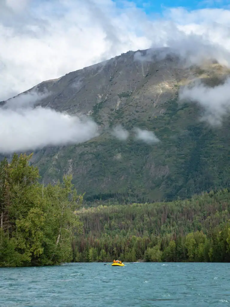 A small yellow raft surrounded by mountains on the Two-Hour Kenai River Scenic Float